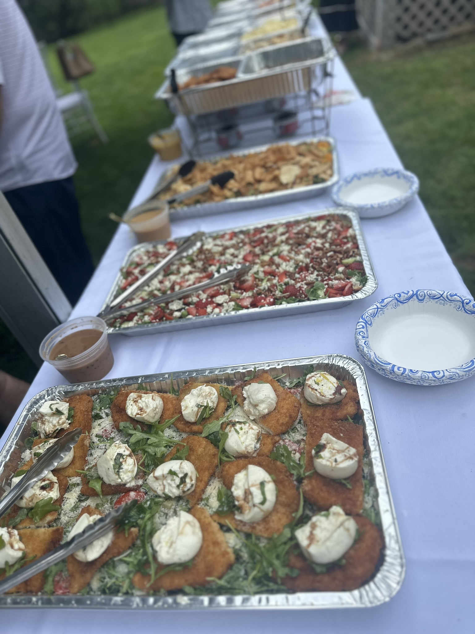 Outdoor buffet with chicken cutlets, burrata, and fresh salads